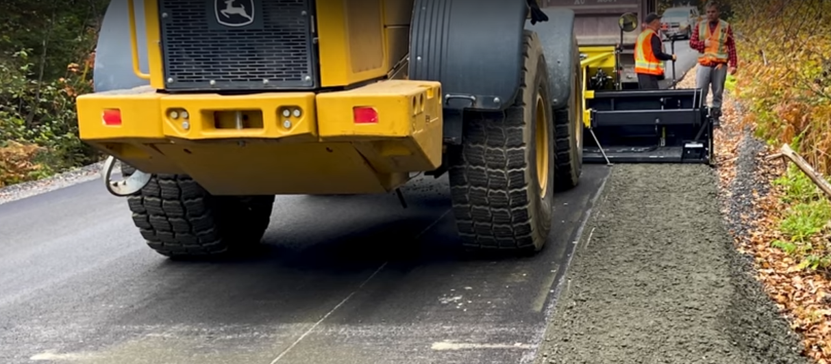 Chargeur qui pave un accotement de route.