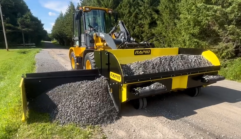 Spreading gravel by a paver on a loader.